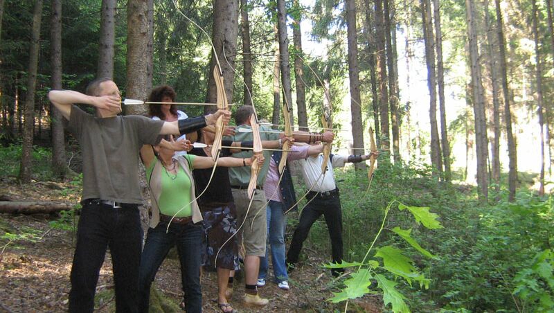 TeamBuilding - Intuitives Bogenschießen - Gruppe im Wald mit Pfeil und Bogen
