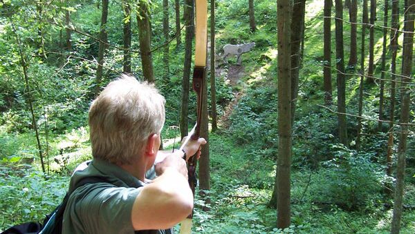 TeamBuilding - Intuitives Bogenschießen - Mann mit Pfeil und Bogen im Wald